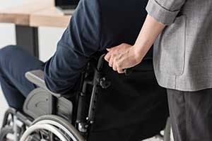 A woman pushing a man in a wheelchair.